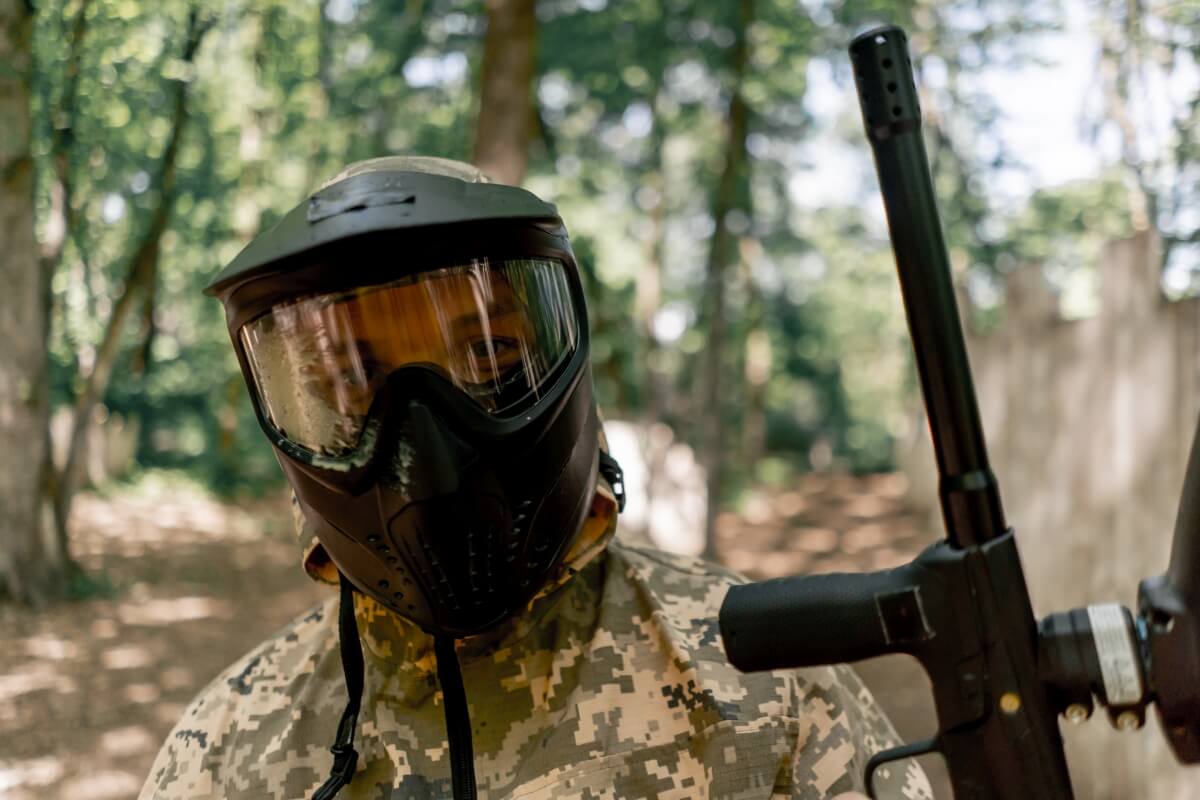 Osoba w masce paintballowej w lesie, idealne miejsce na paintball scenariusze grup szkolnych.