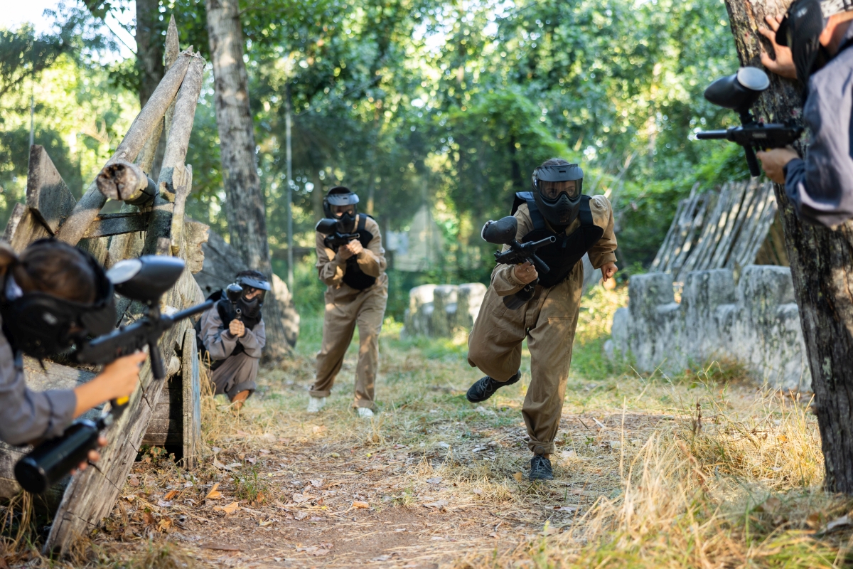 Grupa osób gra w paintball w lesie – co zabrać paintball wieczór kawalerski.