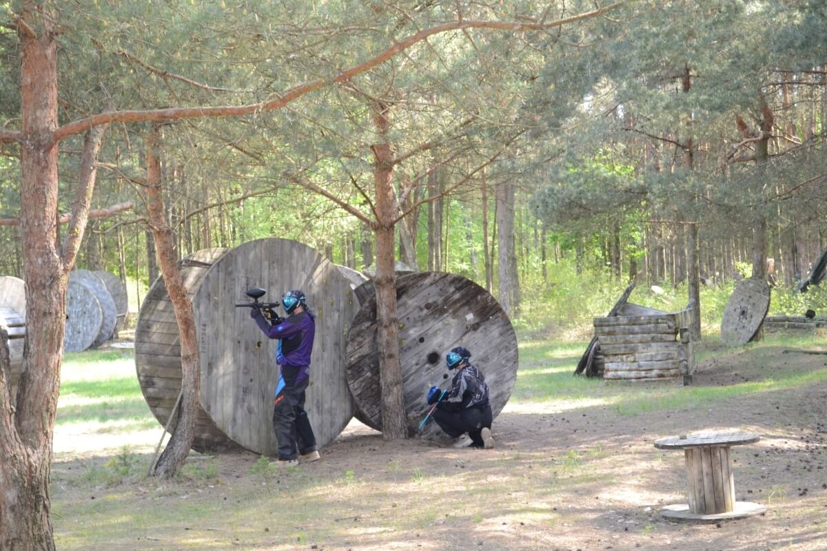 Przygotowanie pola paintballowego specjalne okazje w lesie, z graczami ukrywającymi się za przeszkodami.