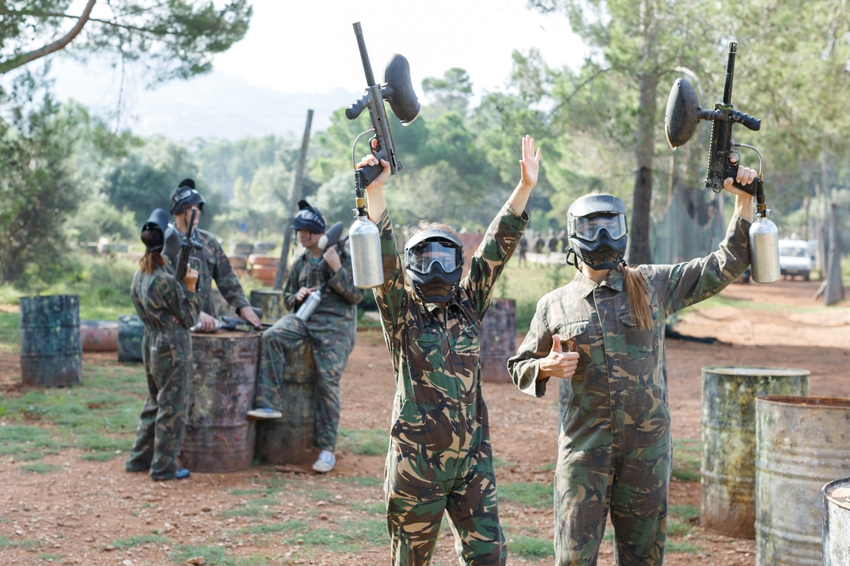 Grupa ubrana w stroje ochronne cieszy się z udanej organizacji paintball grupy na świeżym powietrzu.