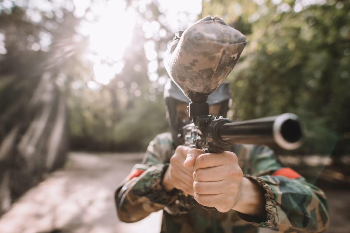 Osoba w masce celująca markerem do paintballa, idealne działanie integracyjne na paintball dla firm.